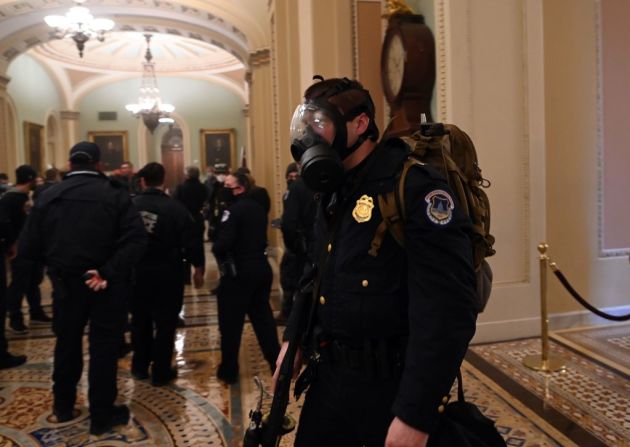 Un agente de policía del Capitolio usa máscara anti gas durante la irrupción de manifestantes armados al Congreso.