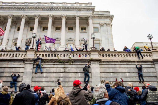 Partidarios del presidente Donald Trump escalan un muro fuera del Capitolio de EE. UU. el miércoles 6 de enero.