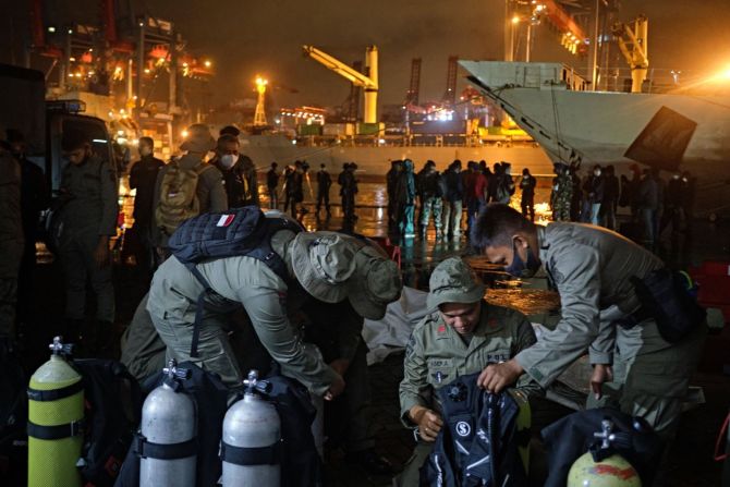 Buzos de la policía indonesia revisan su equipo antes de la llegada del avión de pasajeros indonesio en el puerto de Tanjung Priok este domingo, embarcándose en la operación de búsqueda y rescate.