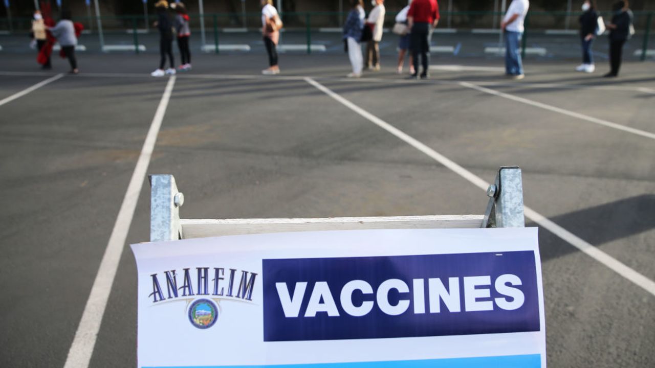 ANAHEIM, CALIFORNIA - JANUARY 13:  People wait in line to receive the COVID-19 vaccine at a mass vaccination site in a parking lot for Disneyland Resort on January 13, 2021 in Anaheim, California. California announced that effective immediately, all residents 65 or older are eligible to receive the vaccine.