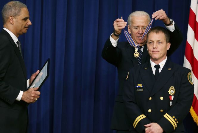 Biden otorga la Medalla al Valor a William Reynolds, un jefe de batallón del Departamento de Bomberos de Virginia Beach, durante una ceremonia en Washington, en febrero de 2013. Biden entregó el premio a los oficiales de seguridad pública que habían demostrado un valor excepcional, independientemente de su seguridad personal, en el intento de salvar o proteger a otros de daños.
