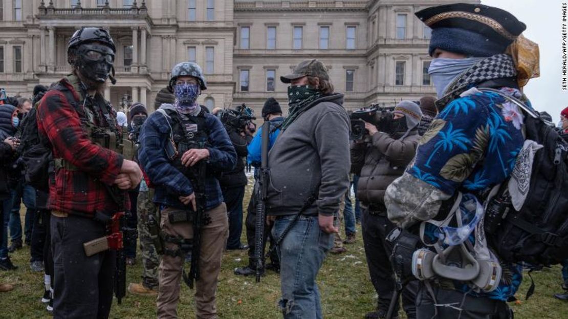 Los manifestantes se paran el domingo con sus armas largas cerca del Capitolio en Lansing, Michigan.