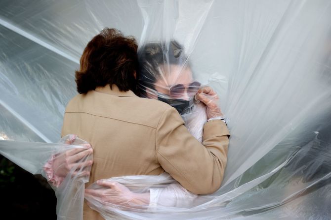 Olivia Grant, a la derecha, abraza a su abuela, Mary Grace Sileo, a través de un plástico que fue colgado para que pudiera abrazarla. En Wantagh, Nueva York, 24 de mayo de 2020.