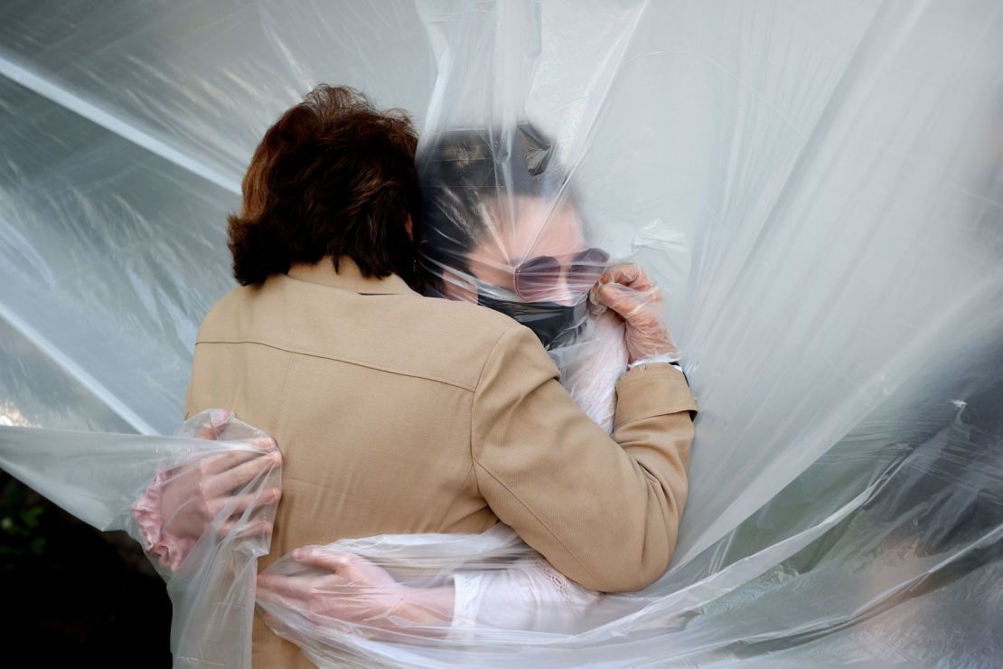 Olivia Grant, a la derecha, abraza a su abuela, Mary Grace Sileo, a través de un plástico que se colgó en un tendedero casero en Wantagh, Nueva York, el 24 de mayo.