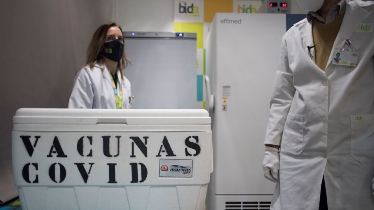 Laboratory technicians stand next to a cool box containing  Pfizer-BioNTech Covid-19 vaccines at the Bidafarma wholesale distribution cooperative in Santa Fe, on the outskirts of near Granada, on January 21, 2021. (Photo by JORGE GUERRERO / AFP)