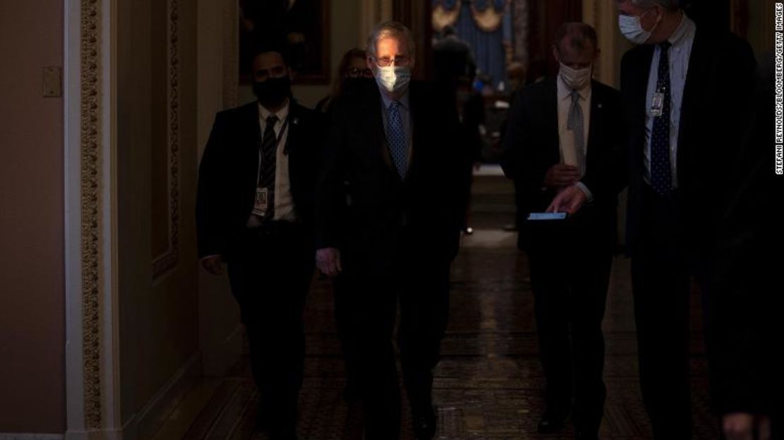 El líder republicano Mitch McConnell, en el centro, usa una mascarilla protectora mientras camina hacia su oficina desde la Cámara del Senado en el Capitolio de Estados Unidos el jueves 21 de enero de 2021.