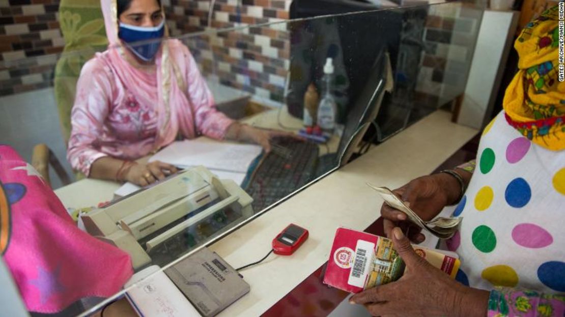 Un agente corresponsal de negocios ayuda a una mujer con una transacción bancaria en Silana, India.