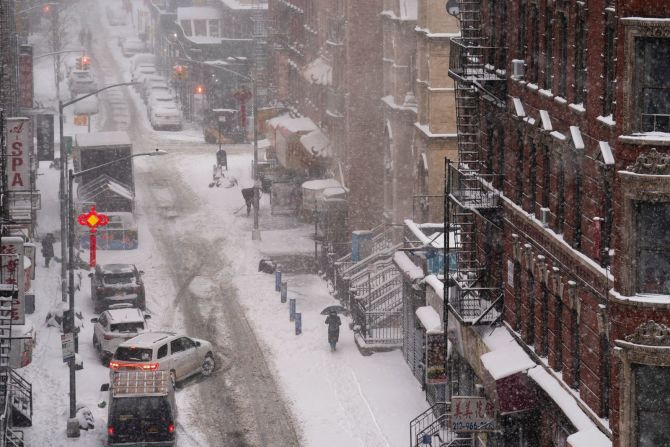 Una peatón camina por una acera cubierta de nieve en el barrio de Chinatown de Nueva York. John Minchillo / AP