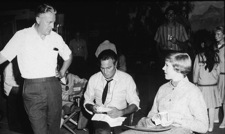 Esta imagen fue tomada en el set de "The Sound of Music" en 1965. El director Robert Wise de pie) conversa con Plummer (en el centro) y con la actriz Julie Andrews.