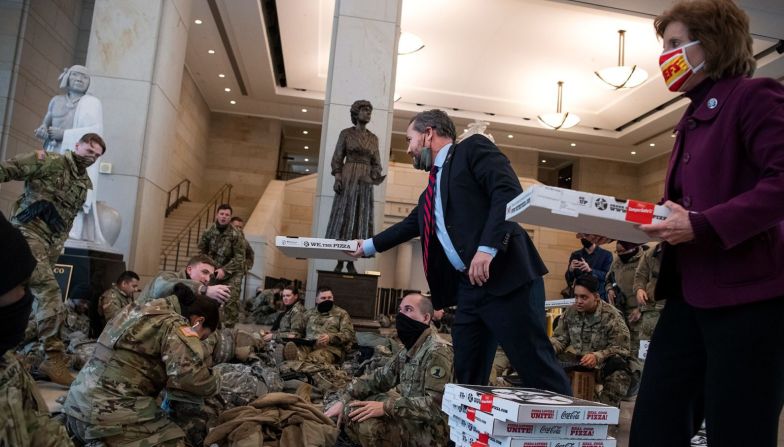 Los representantes Michael Waltz y Vicky Hartzler entregan pizza a miembros de la Guardia Nacional dentro del Capitolio.