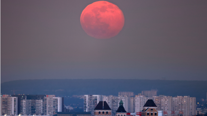 Esta fotografía muestra la luna llena, iluminada en rojo por la puesta de sol, en París el 27 de febrero de 2021.