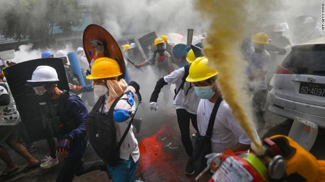 Un manifestante usa un extintor de incendios mientras otros que llevan escudos caseros corren, durante una protesta en Yangon el miércoles.