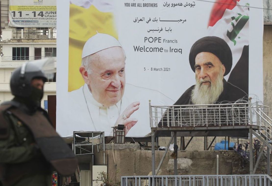 Un guardia de seguridad iraquí frente a un enorme cartel con la imagen del papa Francisco (izquierda), en el centro de Bagdad, el 4 de marzo de 2021, en vísperas de la primera visita del pontífice a Iraq.