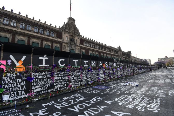 Las vallas colocadas fuera del Palacio Nacional en Ciudad de México fueron intervenidas con nombres de víctimas de feminicidio, consignas y flores.