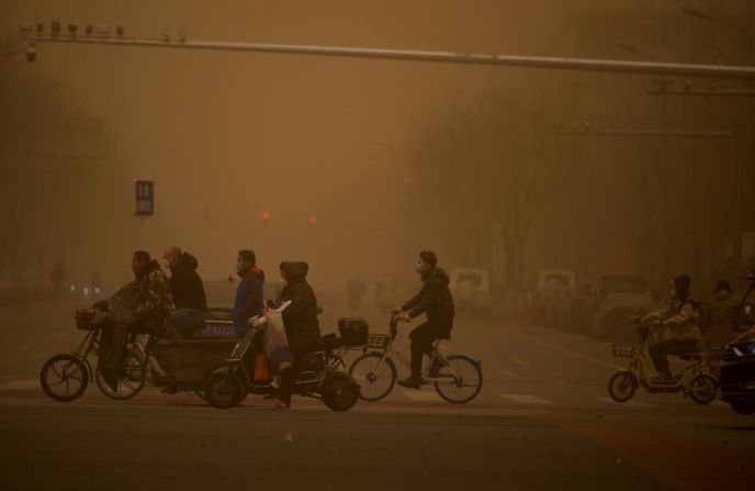 Muchos trabajadores desafiaron las condiciones climáticas y caminaron o montaron bicicleta a través de los fuertes vientos arenosos durante la tormenta de arena en Beijing, China, el 15 de marzo de 2021. Cortesía: Noel Celis/AFP/Getty Images.