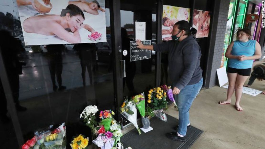 Jessica Lang hace una pausa y coloca su mano en la puerta en un momento de dolor, después de dejar flores con su hija Summer en el salón de masajes asiáticos Youngs, donde murieron cuatro personas.