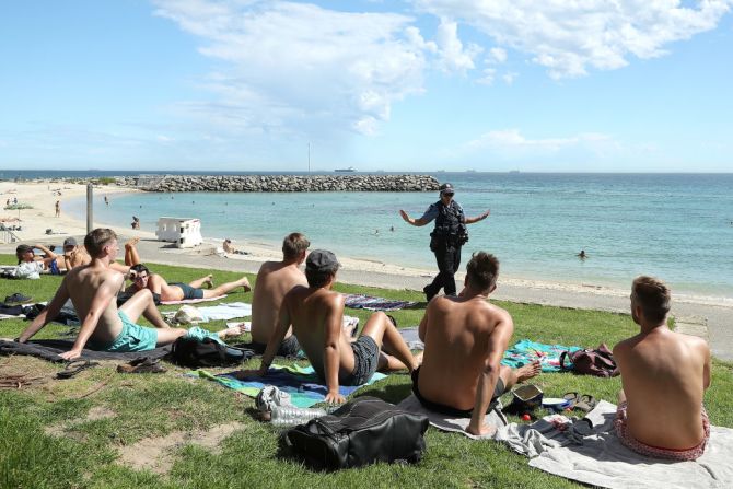 #12: Australia alcanzó el puesto número 12 de los países más felices del mundo, en medio de la pandemia de coronavirus. En esta imagen se puede ver cómo una agente insta a las personas en la playa a mantener el distanciamiento social.