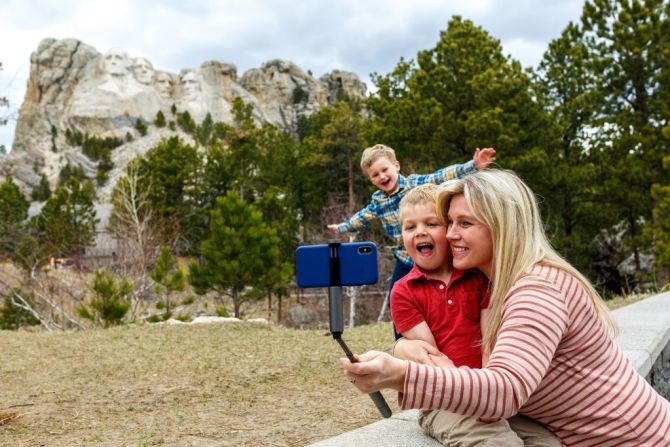 #14: Estados Unidos subió cuatro posiciones este año en la lista de los países más felices del mundo. En 2020 ocupó el lugar número 18. La imagen muestra a una madre y sus dos hijos mientras se toman una foto en el Mount Rushmore National Memorial.