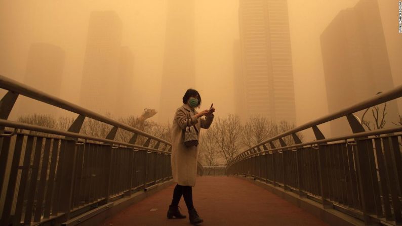 Una mujer camina por un puente peatonal durante una enorme tormenta de arena en Beijing el 15 de marzo.