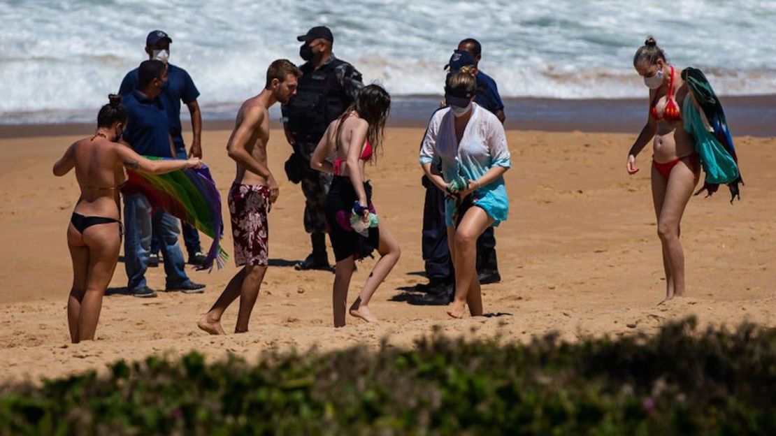 Agentes de policía piden a bañistas que se vayan en Macae, a solo 179 km de la ciudad de Río de Janeiro, donde las playas están cerradas para frenar la propagación del covid-19, el 20 de marzo de 2021 en Macae, Brasil.