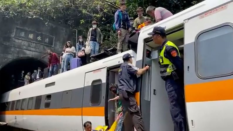 Trabajadores de emergencia ayudan a los sobrevivientes mientras evacuan el tren descarrilado.