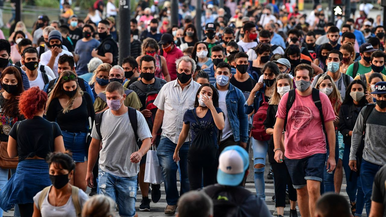 People wearing protective face masks walk by the Brazil Avenue, near the Constitucion train station, in Buenos Aires, on April 6, 2021. - Covid-19 infections in the last 24 hours in Argentina rose to 20,870, a record since the beginning of the coronavirus pandemic, the Ministry of Health reported on Tuesday, April 6. (Photo by RONALDO SCHEMIDT / AFP)