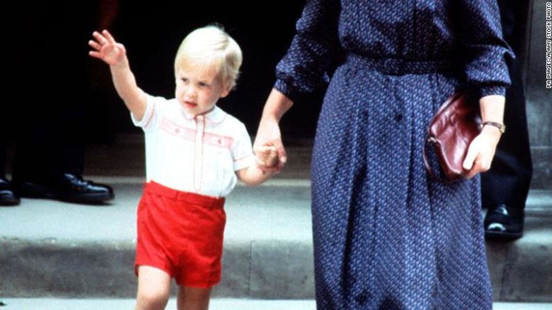 Acompañado por su niñera Barbara Barnes, el príncipe William saluda cuando sale del St. Mary's Hospital después de visitar a su madre y a su hermano recién nacido, el príncipe Harry, el 16 de septiembre de 1984. PA Images / Alamy Stock Photo