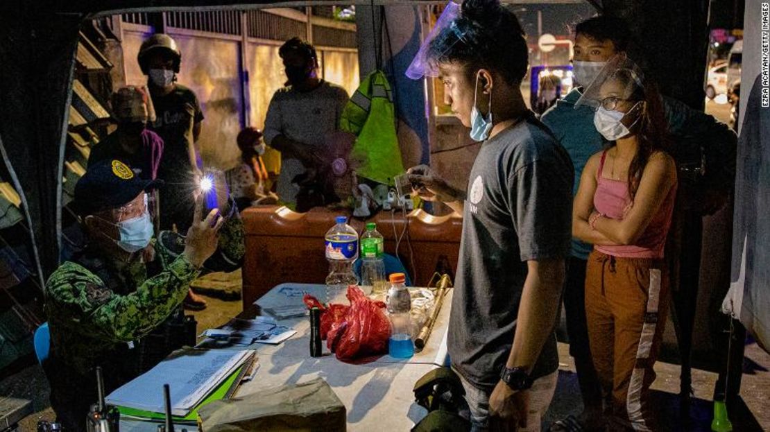 Un agente de policía toma fotografías de presuntos violadores del toque de queda en un puesto de control de cuarentena el 29 de marzo de 2021 en Marikina, Metro Manila, Filipinas.