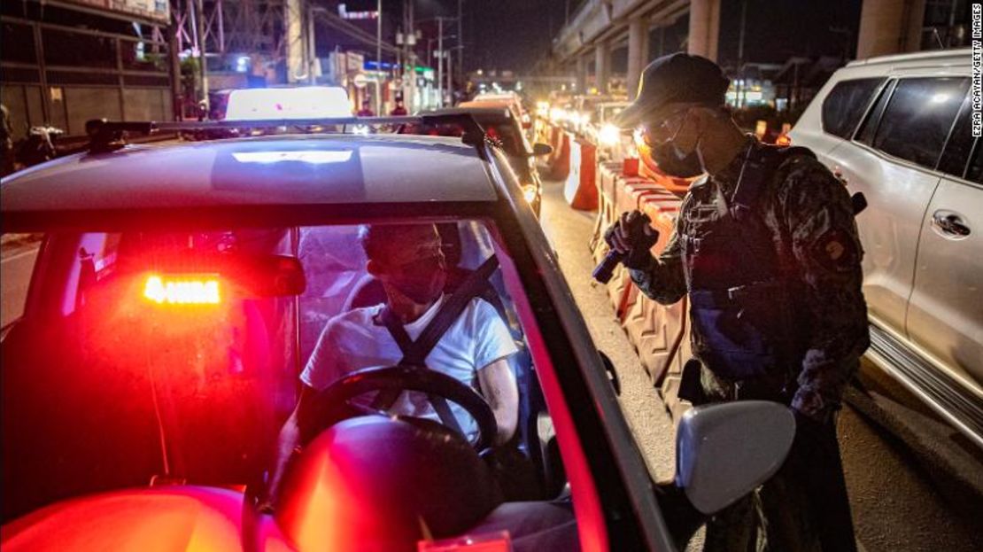 Un agente de policía inspecciona a los automovilistas en un puesto de control de cuarentena el 29 de marzo de 2021 en Marikina, Metro Manila, Filipinas.