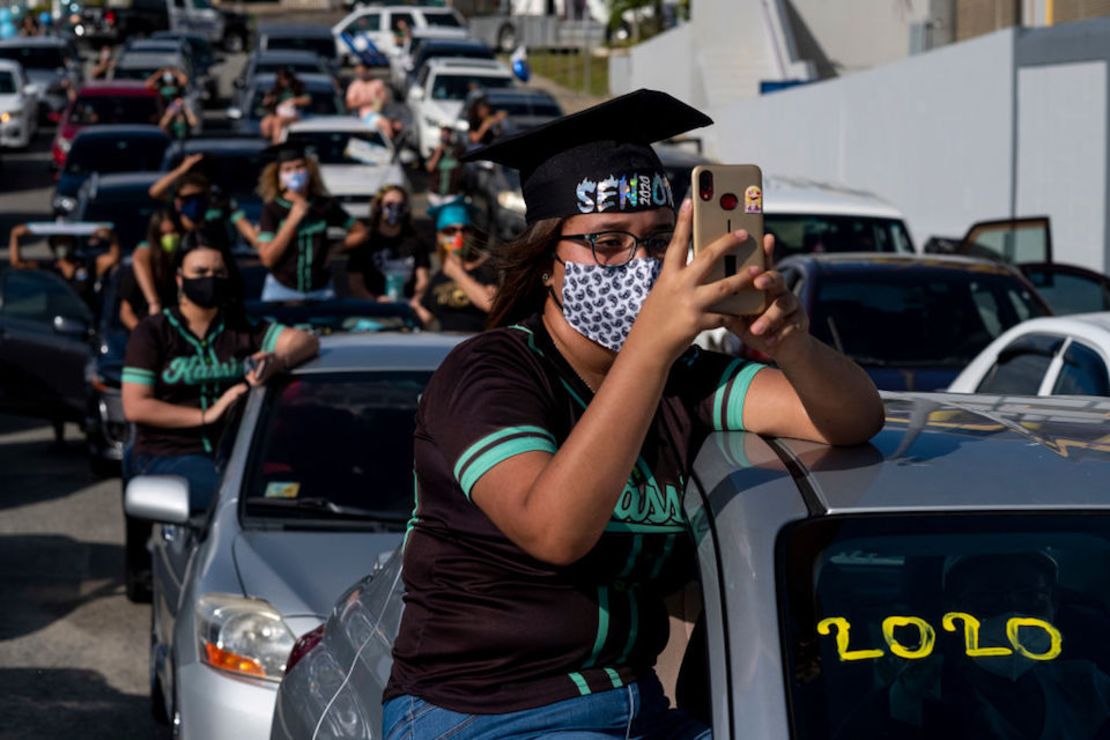 Estudiantes graduados de la Escuela Secundaria Ramon Power Y Giralt usan mascarillas durante una graduación simbólica desde sus autos para mantener la distancia social en un estacionamiento en Las Piedras, Puerto Rico, en mayo de 2020.