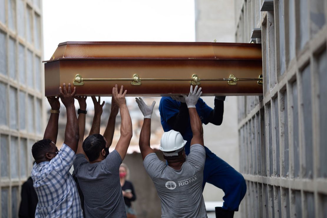 Trabajadores del cementerio y familiares colocan los restos de una mujer que murió por complicaciones relacionadas con el covid-19 en un nicho en el cementerio de Inahuma, en Río de Janeiro (Brasil), el 13 de abril. Silvia Izquierdo/AP