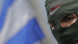 A masked anti-government protester takes part in a demonstration with members of the Nicaraguan Medical Unit (UMN) to demand the re-employment of 405 health workers who lost their jobs for assisting protesters during last year's deadly uprising against President Daniel Ortega, in Managua on August 3, 2019. (Photo by INTI OCON / AFP)