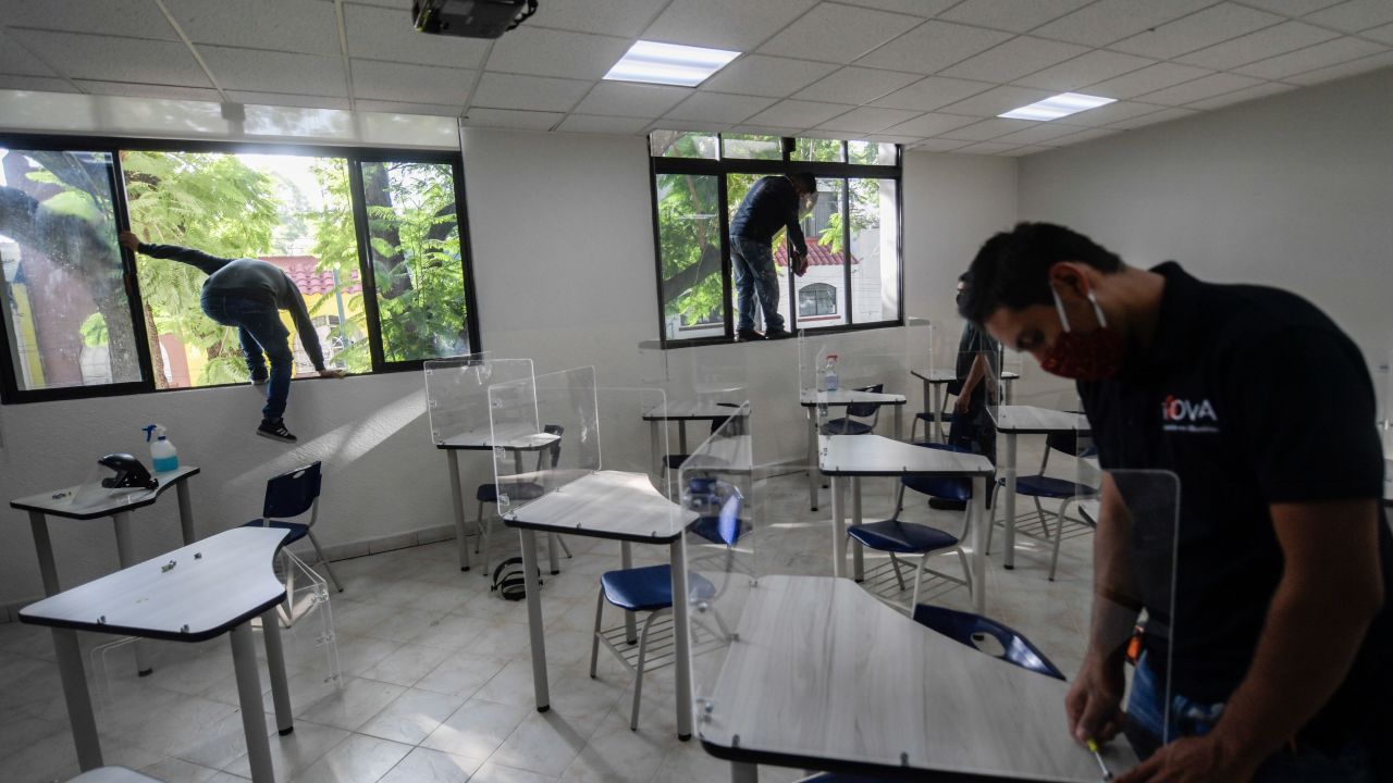 Workers place acrylic shields as a preventive measure against the spread of the novel coronavirus COVID-19 on desks at a Motolinia school classroom in Mexico City, on July 15, 2020, ahead of the reopening of educational facilities. (Photo by Pedro PARDO / AFP)