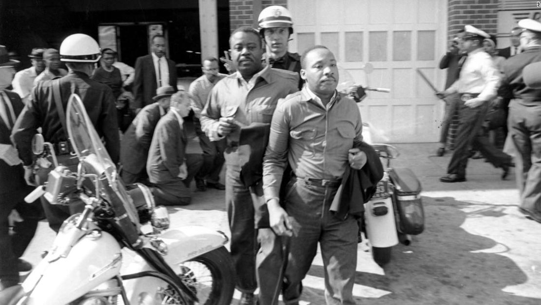 El reverendo Ralph Abernathy (izquierda) y el reverendo Martin Luther King Jr. son escoltados por un policía cuando fueron arrestados en Birmingham, Alabama, el 12 de abril de 1963. Más tarde, King pasó días en confinamiento escribiendo su "Carta desde la cárcel de Birmingham", que conmovió al mundo al explicar por qué los negros no podían seguir esperando un trato justo.