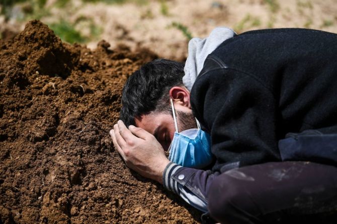 Umar Farooq llora en la tumba de su madre, quien murió de coronavirus, después de su entierro en un cementerio en Srinagar el 26 de abril de 2021. TAUSEEF MUSTAFA / AFP a través de Getty Images.