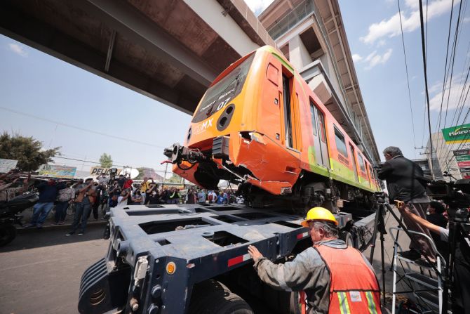 Un tráiler se lleva uno de los vagones del metro que colapsó.