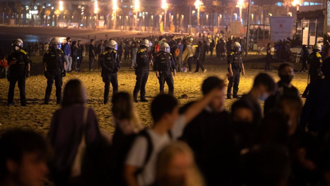 Los agentes de policía montan guardia mientras la gente llena la playa de Barcelona.