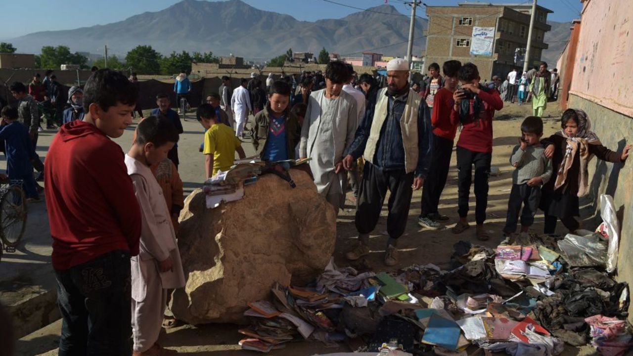 Onlookers stand next to a pile of backpacks and books of victims following yesterday's multiple blasts outside a girls' school in Dasht-e-Barchi on the outskirts of Kabul on May 9, 2021, as the death toll has risen to 50, the interior ministry said. (Photo by WAKIL KOHSAR / AFP)
