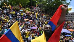 People hold a sign reading Democracy is not in quarantine during protest against a tax reform bill they say will leave them poorer as the country battles its deadliest phase yet of the coronavirus pandemic, in Cali, Colombia, on May 1, 2021. - Colombian President Ivan Duque caved in on April 30 to widespread anger and said he would overhaul the proposed tax reform. Duque announced he was shelving clauses that would lower the income tax threshold to broaden the tax base and raise value-added taxes on goods and services. (Photo by Luis ROBAYO / AFP)