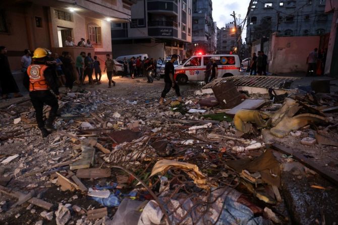 Miembros de la defensa civil palestina revisan los escombros de un edificio destruido por los ataques aéreos israelíes en Gaza el 11 de mayo de 2021.