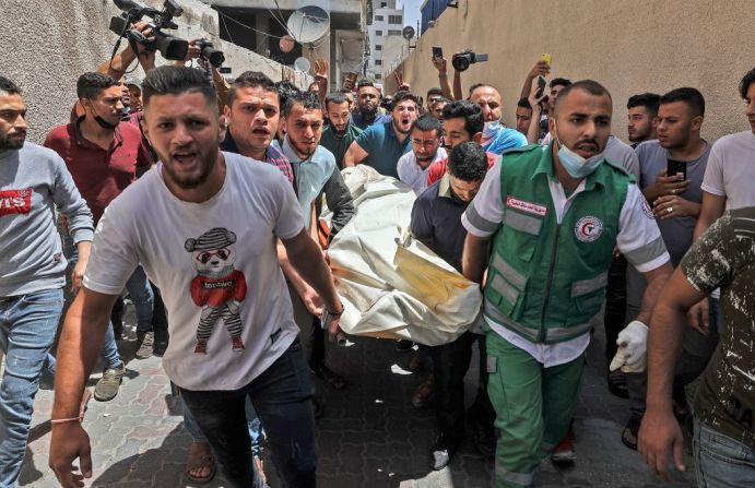 Palestinos evacuan un cuerpo de un edificio atacado por el bombardeo israelí en la ciudad de Gaza el 11 de mayo de 2021.