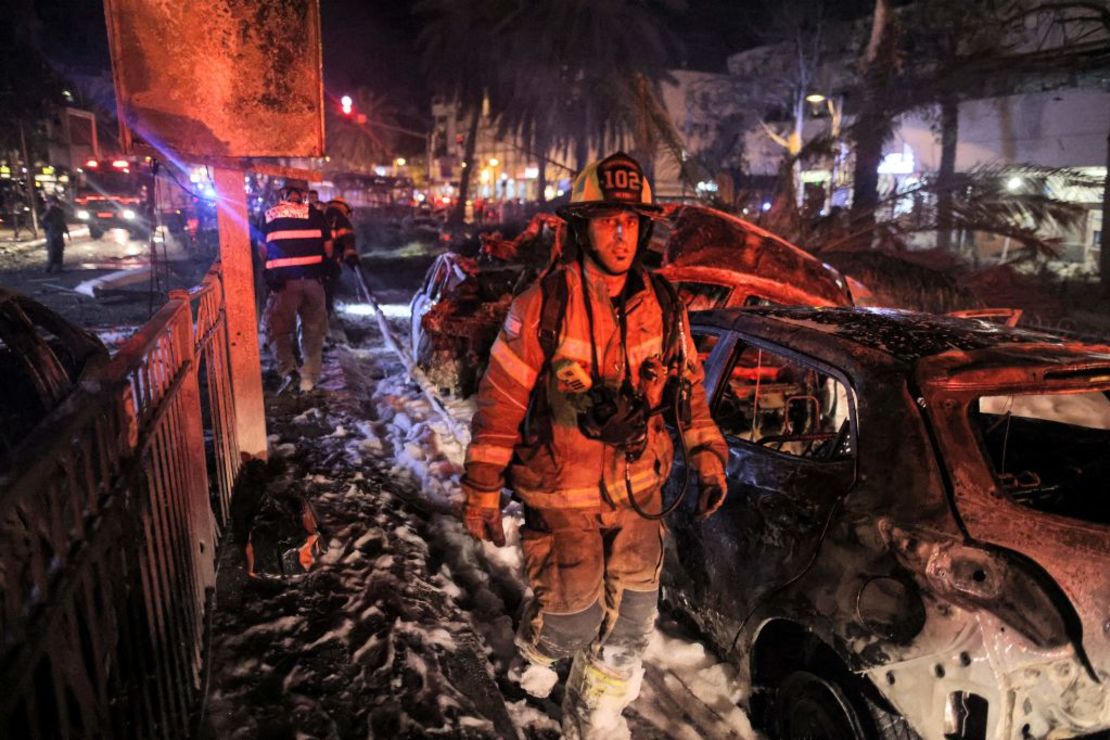 Un bombero pasa junto a un vehículo quemado que se extinguió en el Holon de Israel, cerca de Tel Aviv, el 11 de mayo de 2021, después de que se lanzaran cohetes hacia Israel desde la Franja de Gaza.