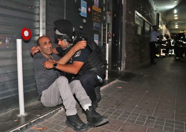Un agente de seguridad israelí consuela a un hombre en la ciudad de Holon cerca de Tel Aviv, el 11 de mayo, 2021.