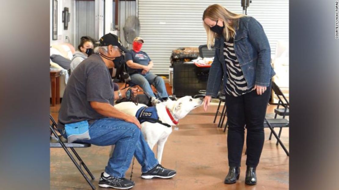 La autora Shauna Springer extiende suavemente el dorso de su mano mientras visita a un perro de servicio en la asociación Operation Freedom Paws.