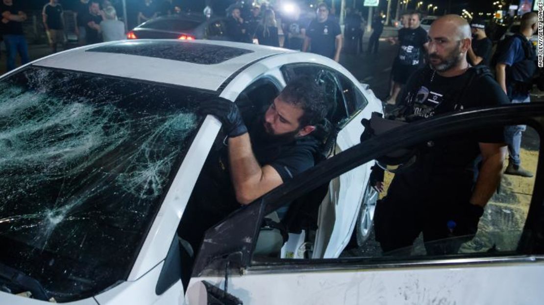 Un policía israelí inspecciona el automóvil de un árabe israelí que fue atacado y herido por una turba el miércoles en Bat Yam, Israel.