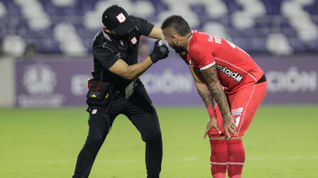 Un asistente ayuda a los jugadores afectados por gases lacrimógenos provenientes de las protestas celebradas fuera del estadio, durante el partido de la fase de grupos del torneo de fútbol Copa Libertadores entre el América de Cali de Colombia y el Atlético Mineiro de Brasil en el Estadio Romelio Martínez en Barranquilla, Colombia.