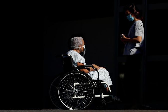 Elizabeth Nader, de 74 años, está acompañada por su nieta mientras espera que una ambulancia la lleve a un hospital en Brasilia, Brasil, el 16 de abril.