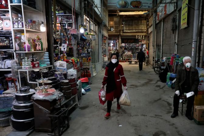 Una mujer con una mascarilla protectora y guantes lleva sus compras a través del bazar Qazvin al noroeste de Teherán, el 22 de abril.