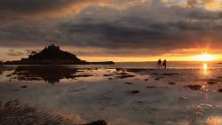 PENZANCE, UNITED KINGDOM - OCTOBER 14:  The sun sets over St Michael's Mount on October 14, 2009 in Penzance, England. The tidal island which has houses, shops, a restaurant, chapel and castle dating back to the 15th century - is owned by the St Aubyn family and is the home of Lord St Levan, but access is managed by the National Trust. Originally the island was thought to have been linked to the mainland but was cut off when Mounts Bay was flooded by the sea in spring tides sometime in the 1100s.