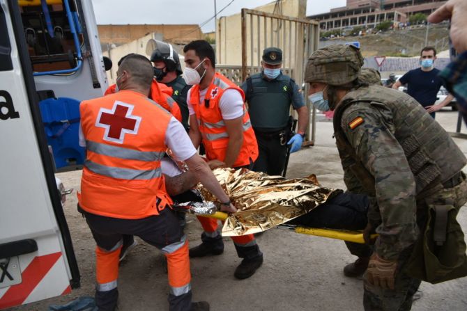 Miembros De la Cruz Roja y soldados españoles trasladan a un inmigrante que llegó nadando a Ceuta desde Marruecos.